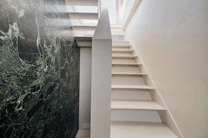 A modern staircase with a marble wall on one side and a plain wall on the other. - Archimede by Wynwood House (Milan)