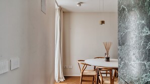 A dining area with a round table, wooden chairs, and a vase of reed diffusers. - Archimede by Wynwood House (Milan)