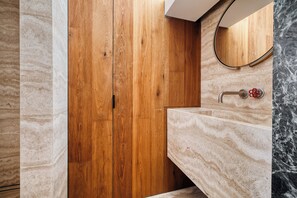 A modern bathroom with a wooden vanity, marble sink, and a curved mirror. - Archimede by Wynwood House (Milan)