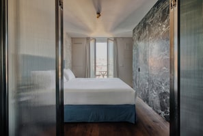 A modern hotel room with a large bed, a view of the outdoors through a window, and a textured wall. - Archimede by Wynwood House (Milan)