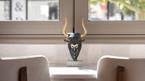 A bull's head sculpture on a window sill between two chairs. - Minotaur's Rest (Heraklion)