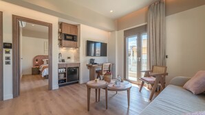 A modern hotel room with a kitchenette, a dining area, a bed, and a view of the city. - Minotaur's Rest (Heraklion)
