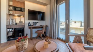 A modern kitchen with a microwave, stove, and refrigerator, a flat-screen TV, a dining area with a table and chairs, and a large window with a view. - Minotaur's Rest (Heraklion)
