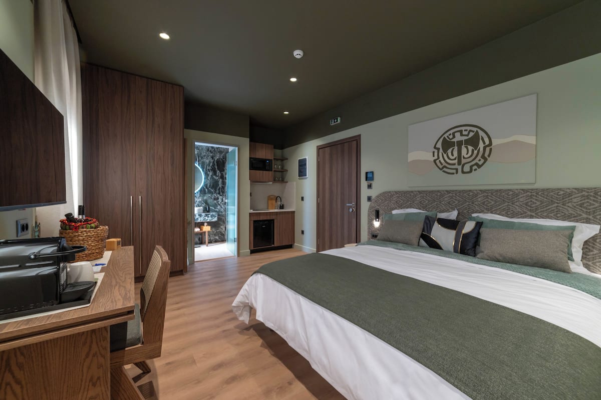 Un dormitorio moderno con una cama grande, un escritorio y vistas a la cocina.