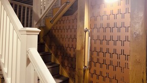 Un escalier avec une rampe en bois et un mur orné d’un motif.