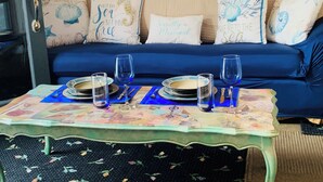Une pièce chaleureuse avec un canapé bleu agrémenté de coussins décoratifs, une petite table mise avec des assiettes et des verres, et un mur en bois en arrière-plan.