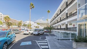 A parking lot with cars, a pedestrian crossing, and a modern building with balconies. - Beachfront 1BR with Balcony, Pool & Parking Ancla (Callao Salvaje)