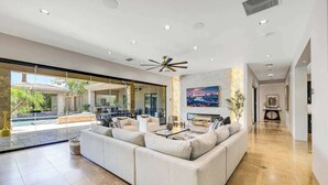 Ein geräumiges Wohnzimmer mit einem großen Ecksofa, einem Couchtisch und einem Stadtbild an der Wand.
