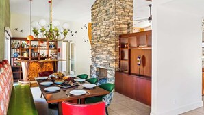 Ein Essbereich mit Steinwand, Holztisch und grünen Stühlen.