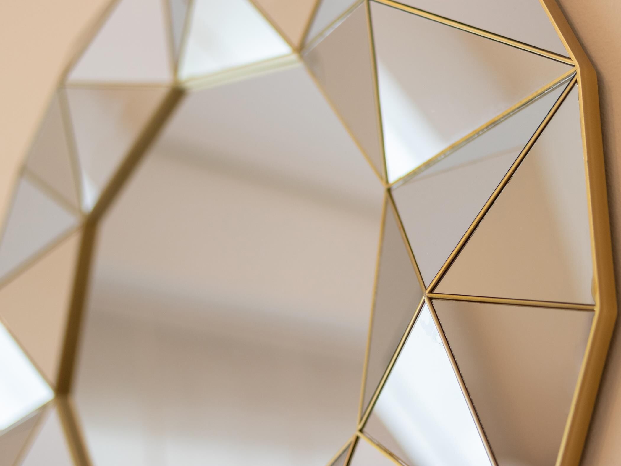 Espejo de pared con marco dorado y diseño geométrico.