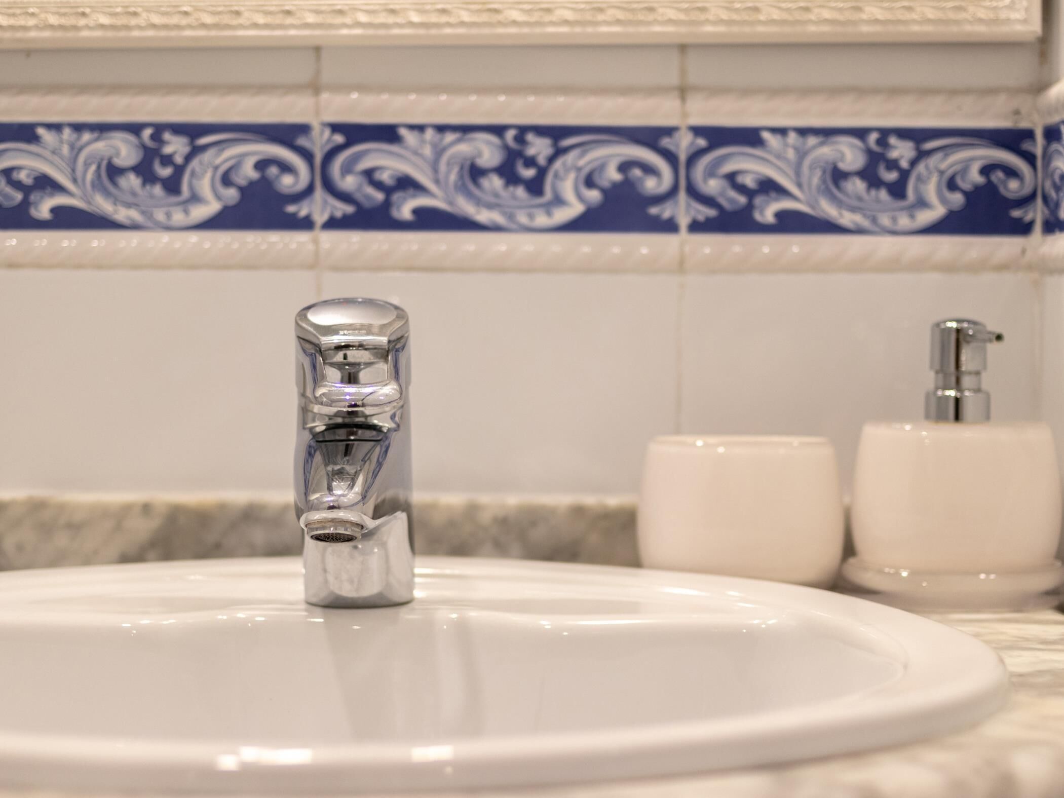 A bathroom sink with a modern faucet, a soap dispenser, and a toilet paper holder.