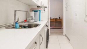 A compact kitchen with a sink, a coffee maker, and a small cabinet.