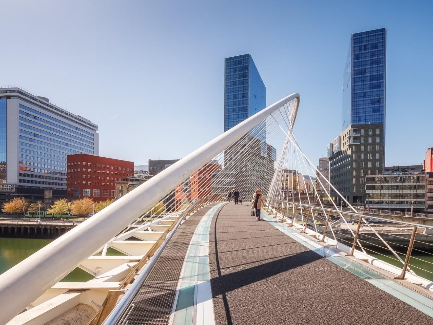 Un pont piétonnier doté d’une structure métallique blanche et d’une passerelle au revêtement décoratif.