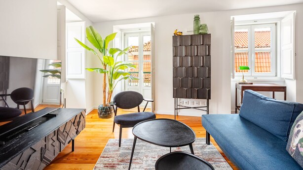 Ein modernes Wohnzimmer mit einer Couch, Sesseln, einem Fernseher und einem Bücherregal.