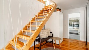 Eine Holztretreppe mit einem Seilschutznetz, einer gepolsterten Bank und einem kleinen Hocker in einem modernen Küchenbereich.