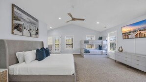 Una camera da letto con un letto grande, una ventola a soffitto e un televisore appeso al muro.
