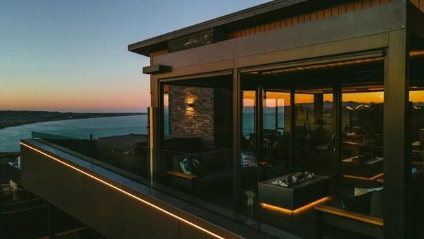 A modern building with a glass facade overlooking a body of water. - Tirohanga Nui (Oamaru)