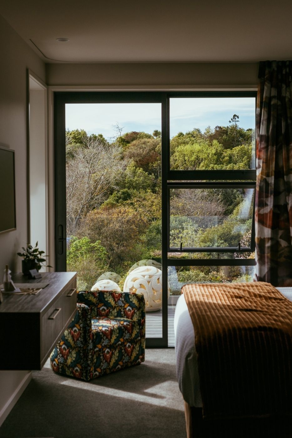 A bedroom with a large sliding glass door leading to a scenic outdoor view.