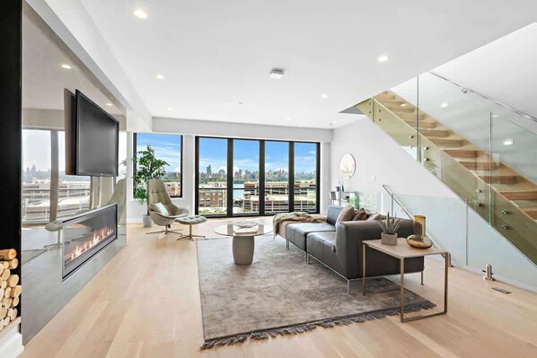A modern living room with a fireplace, a sofa, a coffee table, and a staircase.