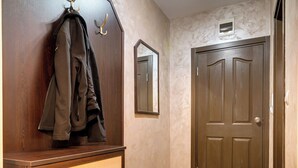 Ein Flur mit einem Holzschrank, einem Kleiderständer, einer Tür und einem kleinen Regal.