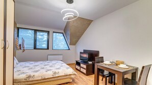 Ein Schlafzimmer mit Bett, Schreibtisch, Fernseher und Fenster.