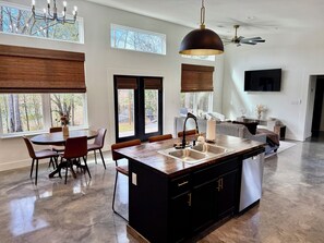 Una cocina moderna con una isla central, ventanas amplias y un comedor con sillas.