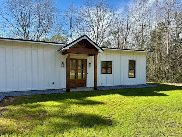 A single-story building with a front door, two windows, and a small porch.