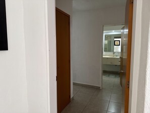 A hallway leading to a bathroom with a mirror, sink, and toilet. - Awake to the Sea - Private beachfront apartment - Nuevo Vallarta (Bucerías)
