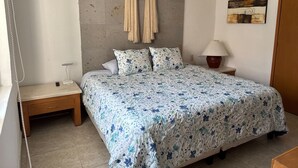 Een slaapkamer met een bed, nachtkastjes, een lamp, een handdoekhouder aan de muur en een schilderij.