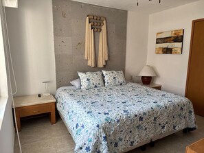 A bedroom with a bed, bedside tables, a lamp, a wall-mounted towel rack, and a painting. - Awake to the Sea - Private beachfront apartment - Nuevo Vallarta (Bucerías)