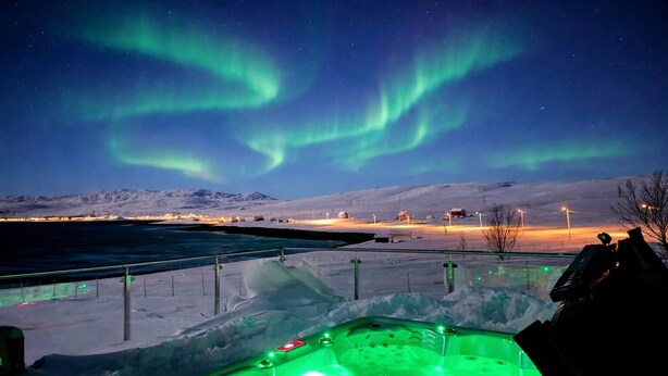A hot tub in a snowy outdoor setting with a view of the Northern Lights.