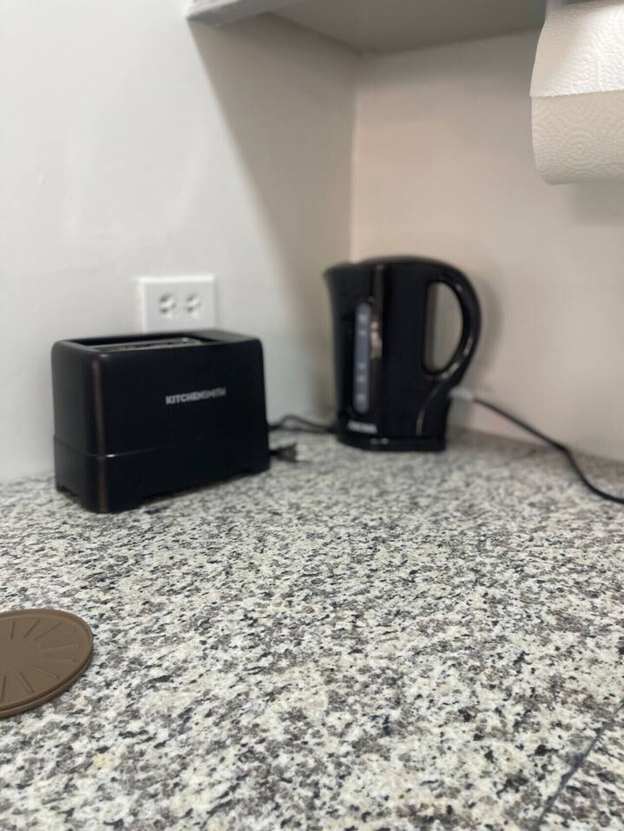 Ein Küchenbereich mit einem Toaster, einer Kaffeemaschine und einer Münze auf einer Granitarbeitsplatte.