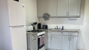 A compact kitchen with white cabinets, a built-in oven, a microwave, and a sink. - Quiet 1BR: 4 mins to Beach 10 mins to Downtown (Nassau)