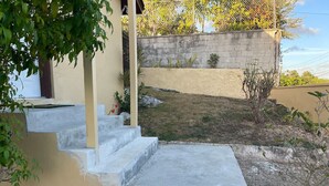 A concrete staircase leading to a house with a beige exterior wall and a small garden area. - Quiet 1BR: 4 mins to Beach 10 mins to Downtown (Nassau)