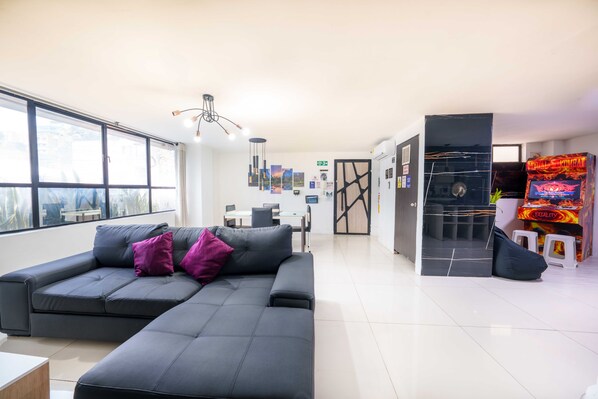 A modern living area with a sofa, a gaming console, and a view of the outside. - 2 bedroom apartment 1 block Lleras park (Medellín)