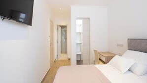 Ein Hotelzimmer mit einem Bett, einem Schreibtisch und einem an der Wand befestigten Fernseher.
