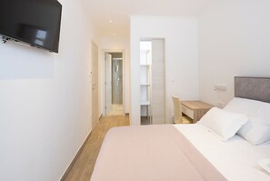 A hotel room with a bed, a desk, and a TV mounted on the wall. - Family-Friendly 5-Bedroom Villa with Pool & Outdoor Space (Kaštel Kambelovac)