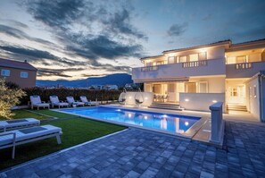 A modern two-story house with a swimming pool, outdoor seating, and a view of the mountains. - Family-Friendly 5-Bedroom Villa with Pool & Outdoor Space (Kaštel Kambelovac)