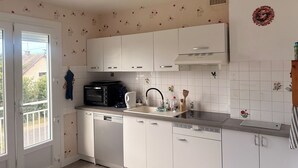 Una cucina con mobili bianchi, lavastoviglie, forno a microonde e macchina da caffè.