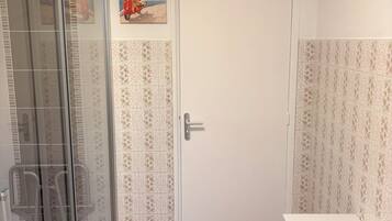Un baño con baldosas estampadas, una puerta blanca y un cartel en la pared.