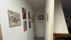 Un corridoio con pareti bianche e pavimento in legno. Diverse immagini incorniciate adornano le pareti.