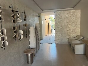 Ein modernes Interieur mit minimalistischem Design, das einen langen, mit einem Muster versehenen Gang, eine Sitzecke mit Sofas und eine einzigartige Wandskulptur zeigt.