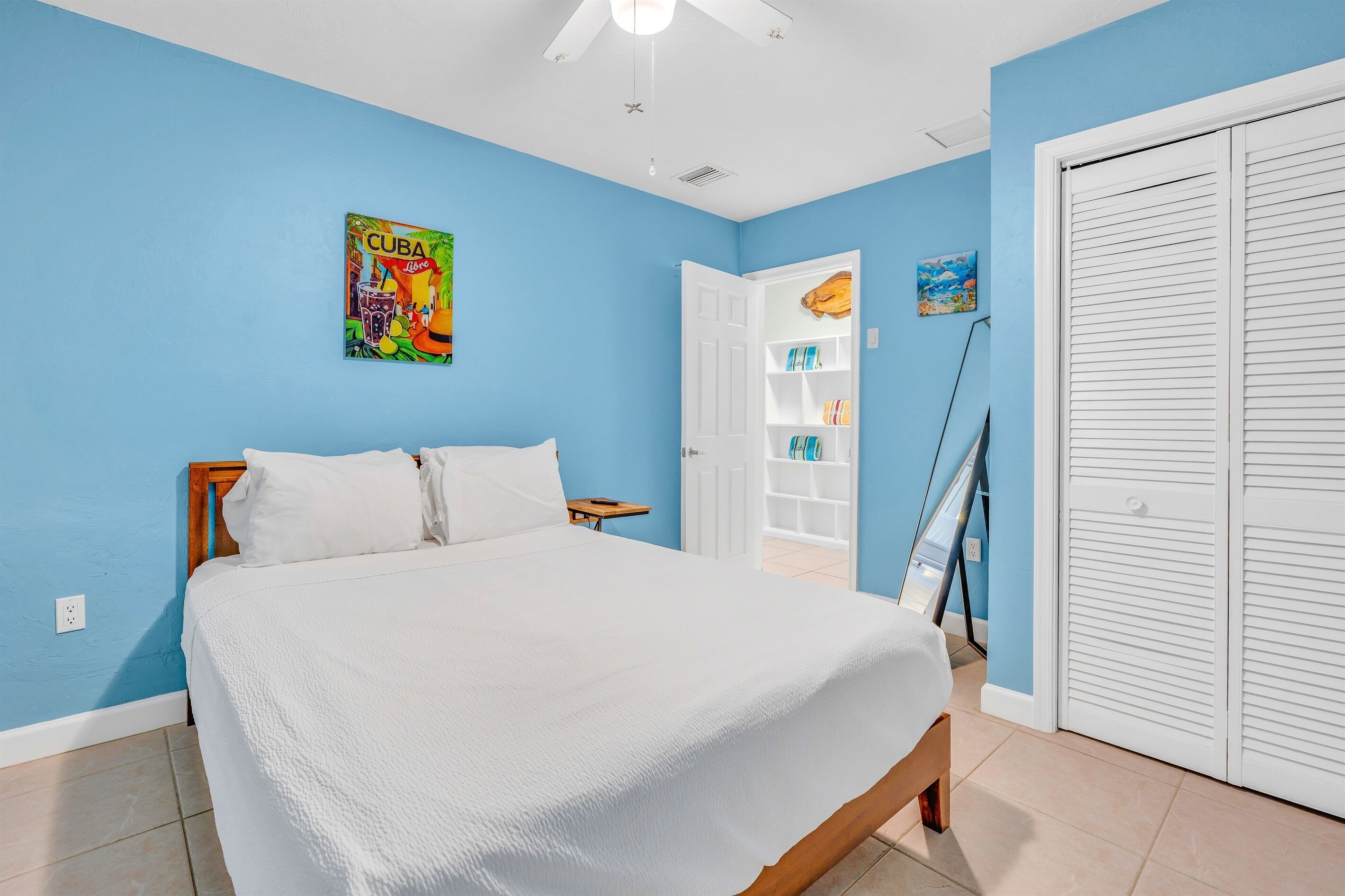 A bedroom with a bed, a white door, and a blue wall.
