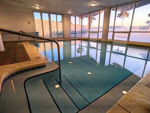 An indoor swimming pool with clear glass walls, a tiled floor, and a metal handrail. - Sunset Balcony + 2 King Suites + Beach Gear (Fort Walton Beach)