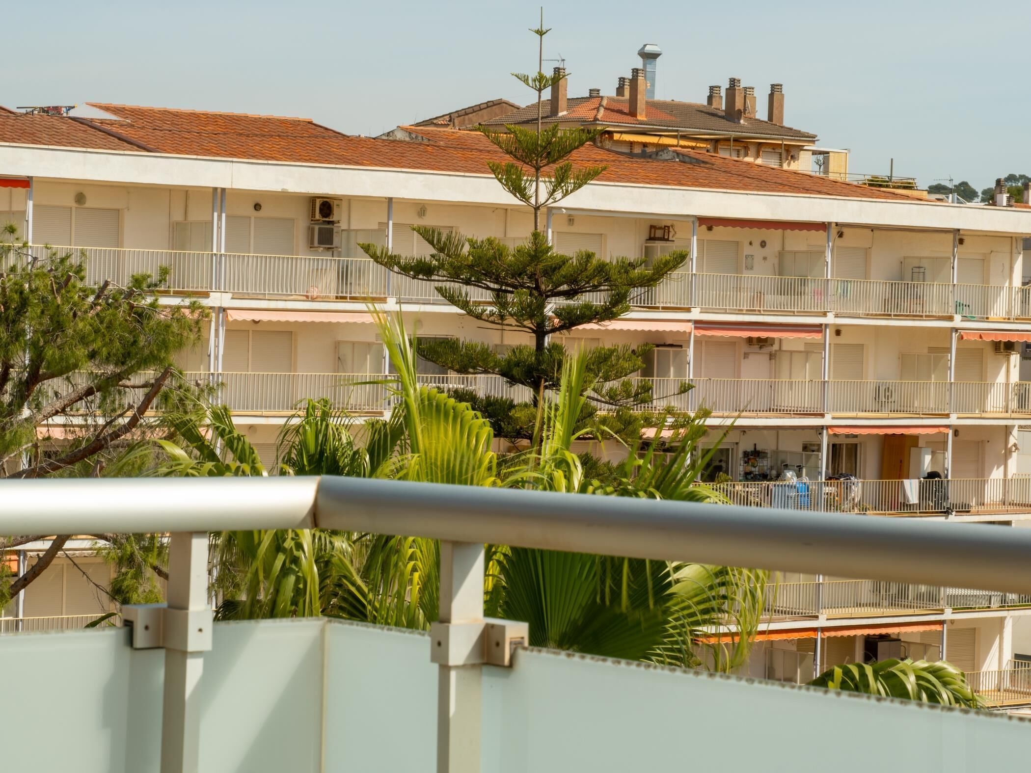 A multi-story building with balconies, a flat roof, and a clear sky.