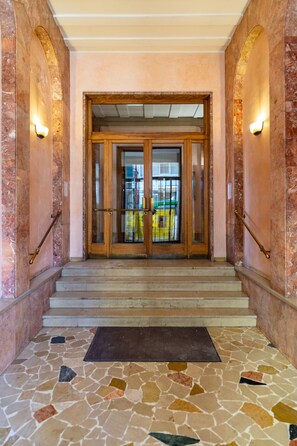 A grand entrance with a marble staircase leading to a glass door. - Aida | Monolocale centrale per 2–3 ospiti (Verona)