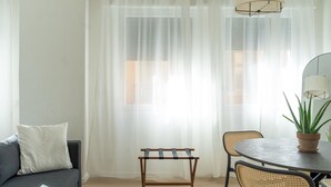 Een woonkamer met een bank, een bijzettafeltje met stoelen en een potplant.
