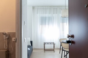 Ein Hotelzimmer mit einem Bett, einem kleinen Tisch, einem Stuhl und einem Fön an der Wand.