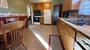 A compact kitchen with wooden cabinets, a refrigerator, stove, and a microwave. - Spacious 4-bedroom house in Fairmont (Fairmont)