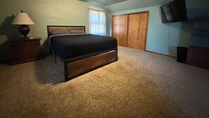 A bedroom with a bed, a nightstand, a lamp, a TV, and a closet. - Spacious 4-bedroom house in Fairmont (Fairmont)